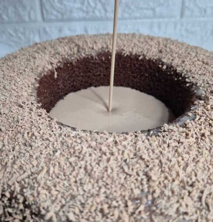 Rosca grande de Turín relleno de una crema que se está vertiendo desde arriba en un chorro fino.